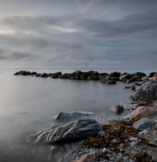 Klippor vid kusten under en mulen himmel, med havet i bakgrunden.