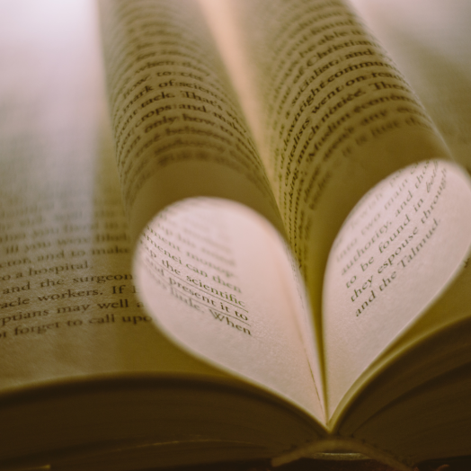 Pages of a book folded to form a heart shape, with text visible on the pages.