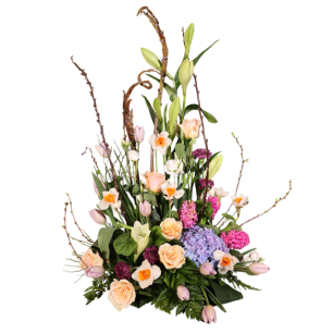 En blomsterarrangemang med liljor, rosor, tulpaner och hortensior i olika färger, omgiven av grenar och gröna blad.